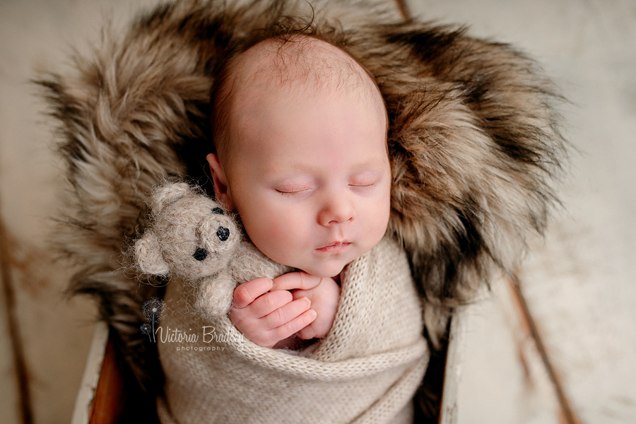 baby newborn boy holding small teddy 