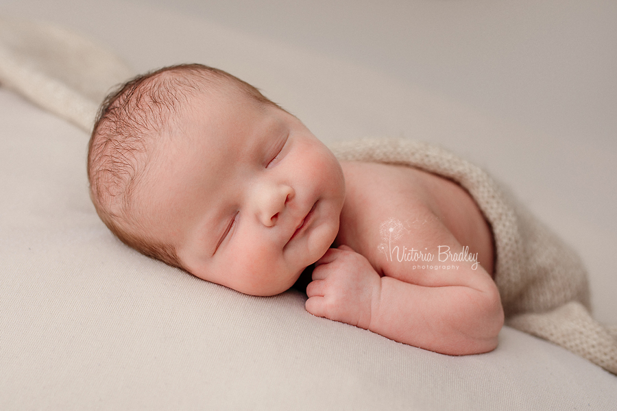 wrapped newborn baby photography, baby on tummy on oatmeal backdrop