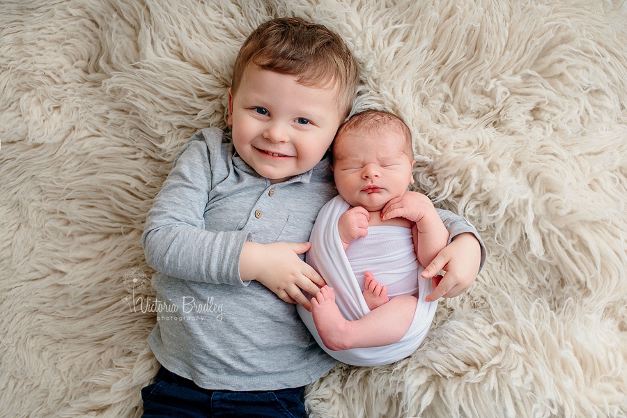 newborn and sibling image from newborn photography session on cream flokati