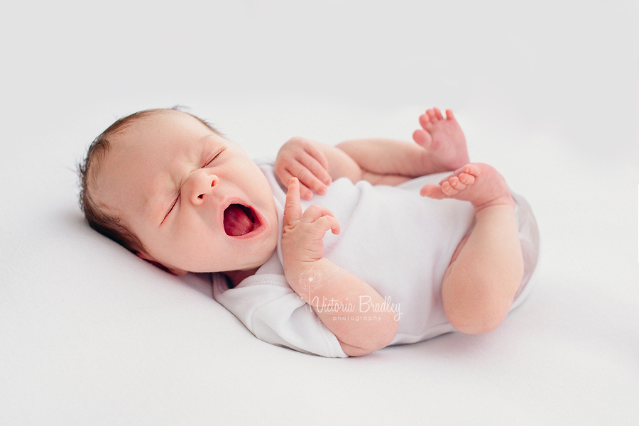 natural newborn photography yawning newborn on white backdrop