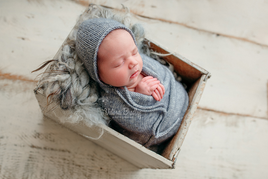 baby wrapped in crate in grey