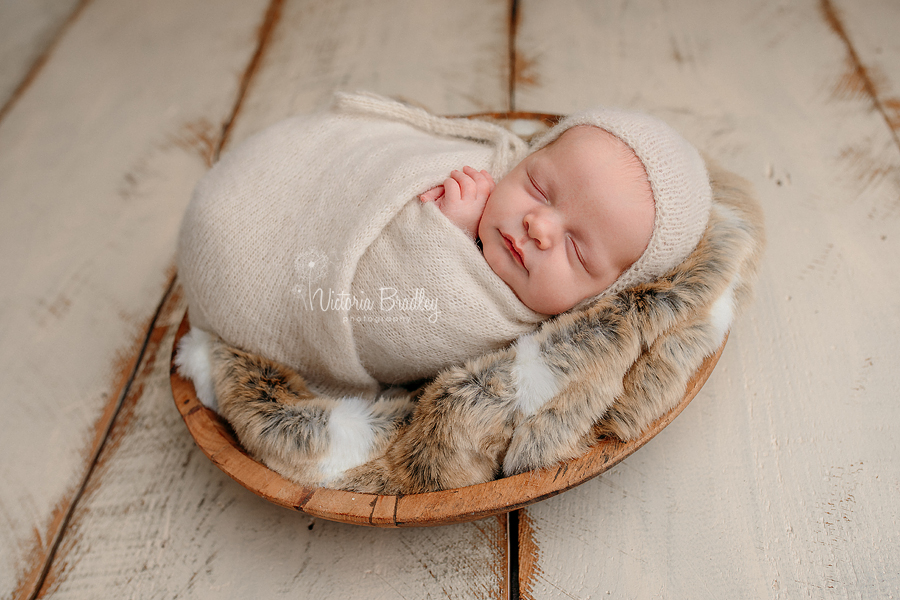 wrapped newborn baby boy in cream