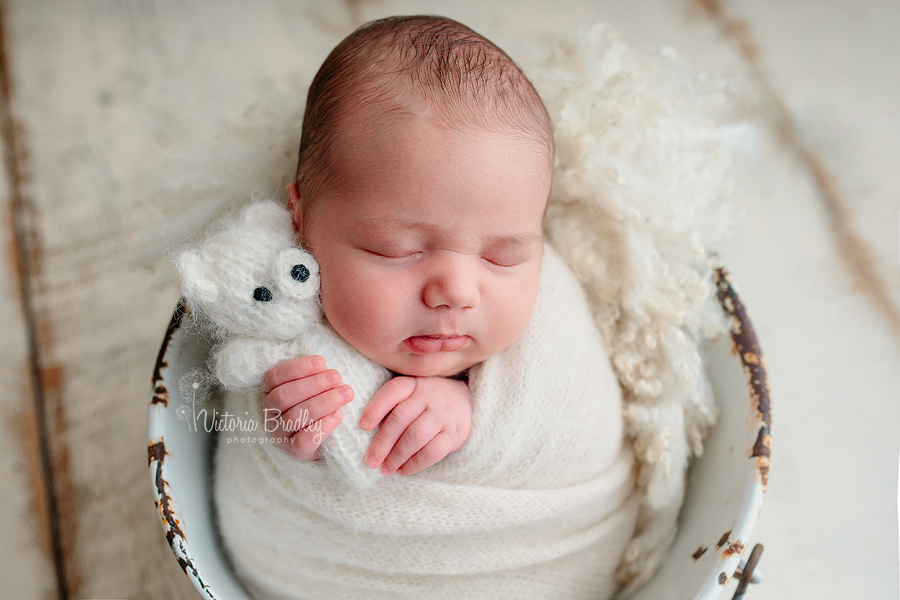 baby wrapped in bucket with bear