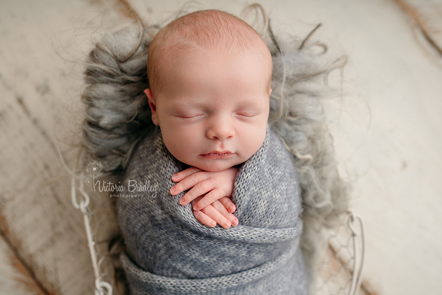 wrapped newborn in basket in grey wrap