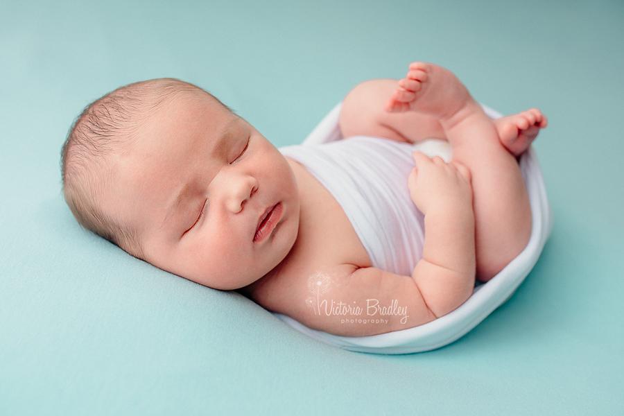 newborn wrapped in white on blue blanket