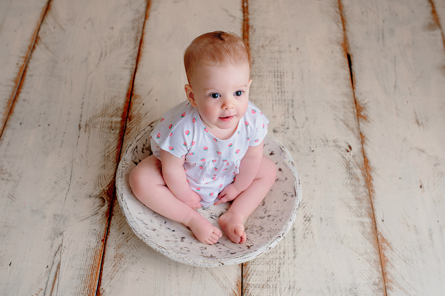 baby girl sat in a white wooden bowl