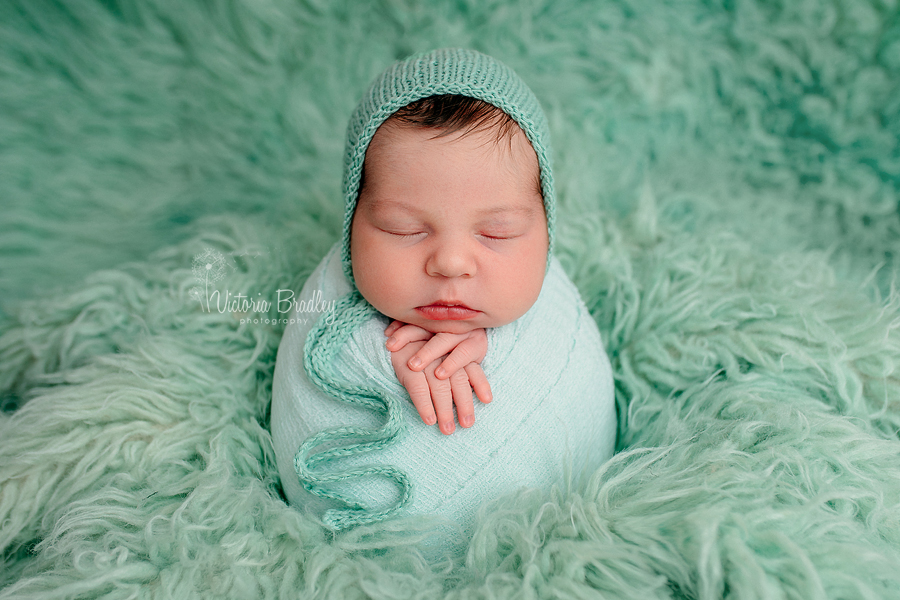 wrapped baby on mint green flokati