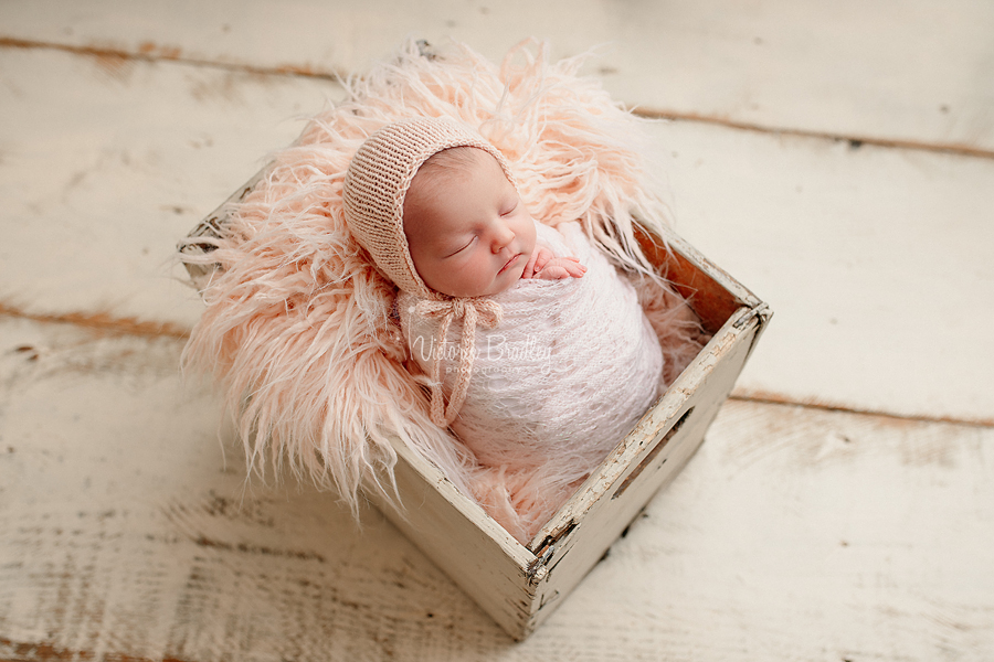 wrapped newborn in crate, pale pinks