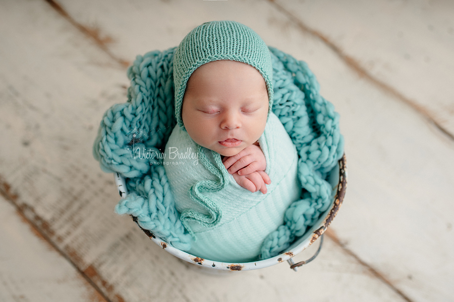 wrapped newborn with mint stuffer and wrap, white bucket