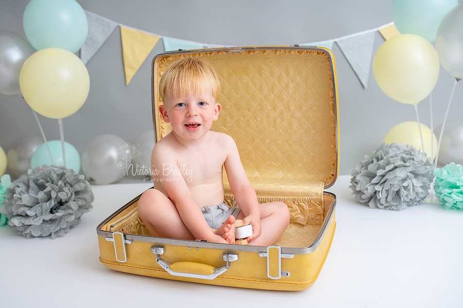 2 year old boy sat in a yellow suitcase