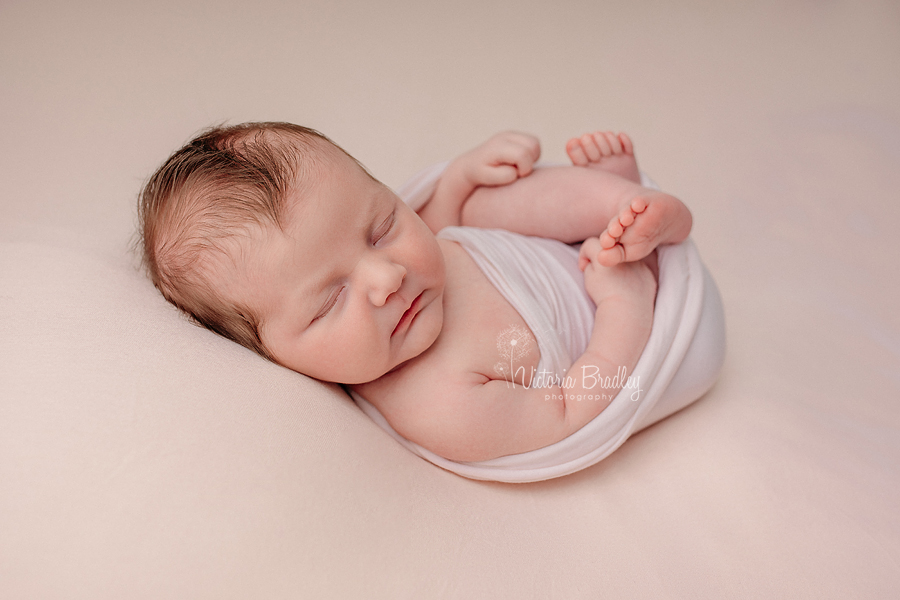 wrapped baby on peach backdrop