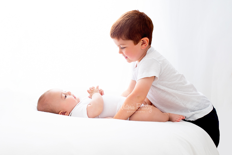 sibling and baby white room