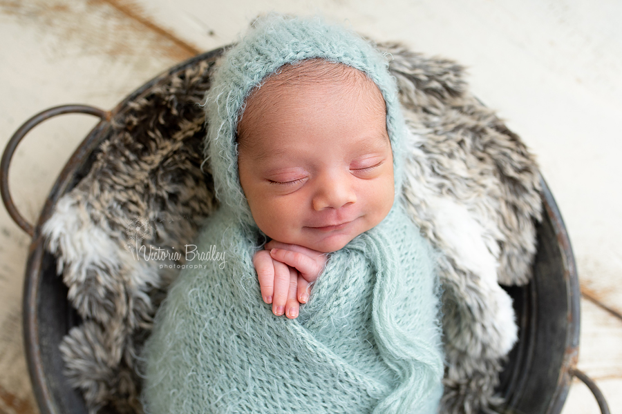 smiling newborn wrapped in sage wrap