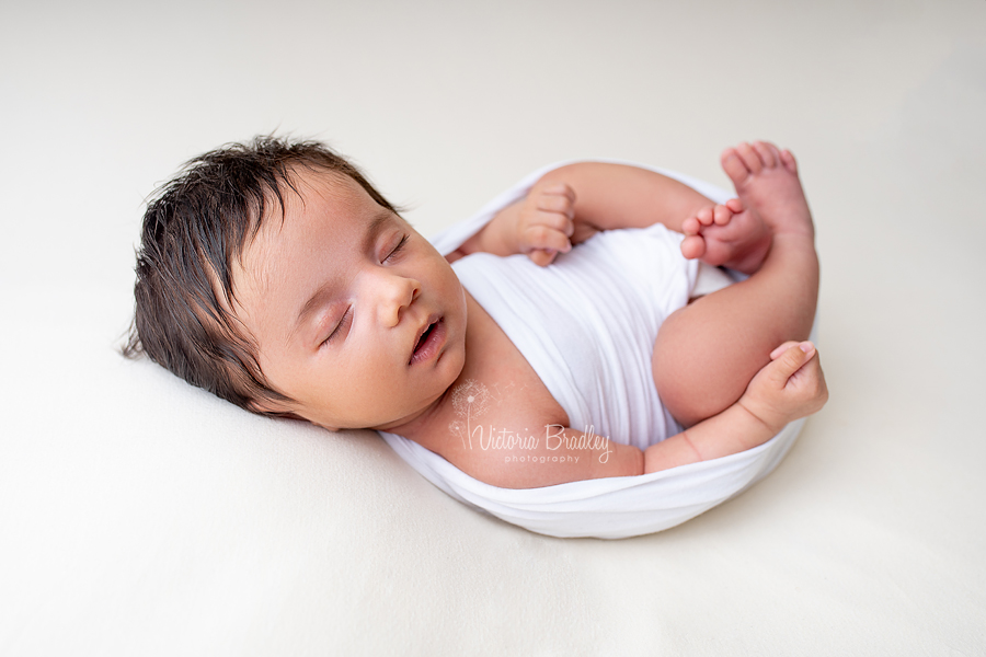 asleep older newborn wrapped up on pale yellow