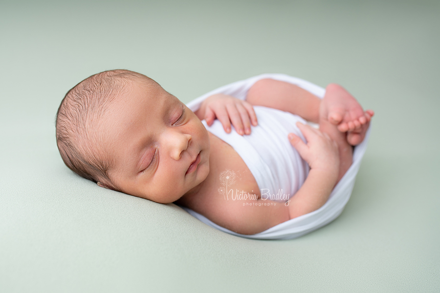 wrapped newborn on sage backdrop