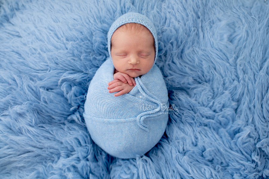 wrapped baby on blue flokati rug