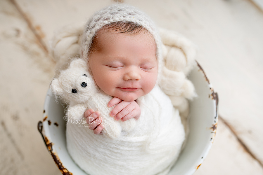 wrapped baby holding mini teddy 