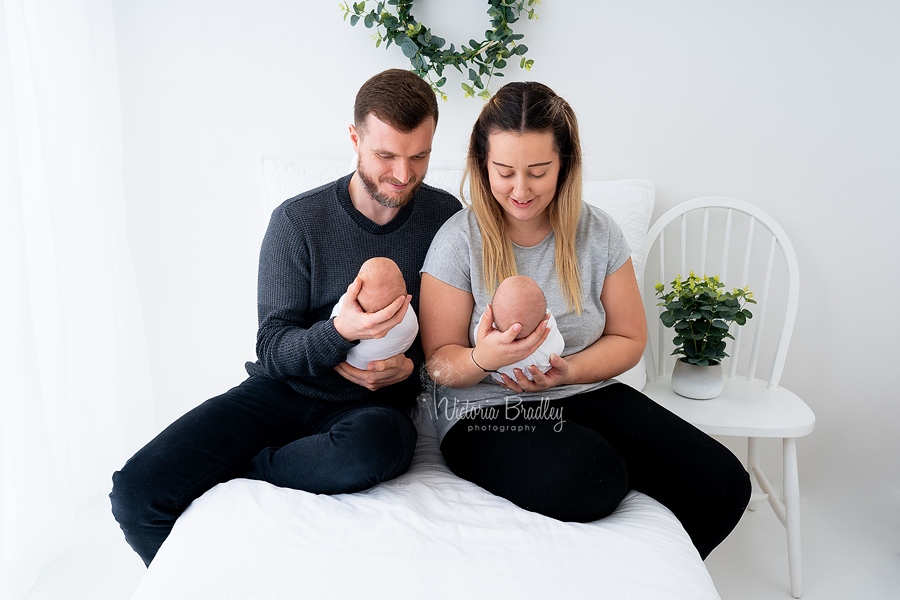 newborn twins with parents, white room set up