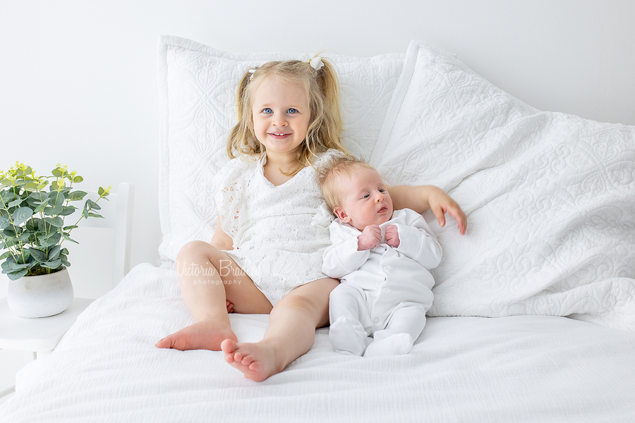 sibling and newborn on white room set