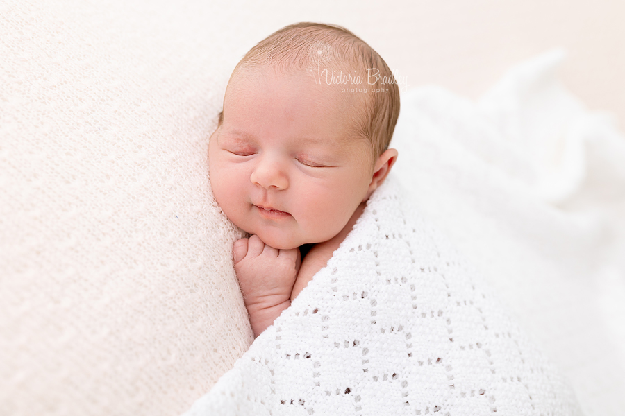 baby newborn girl on tummy with white blanket