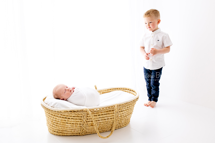 sibling and newborn moses basket