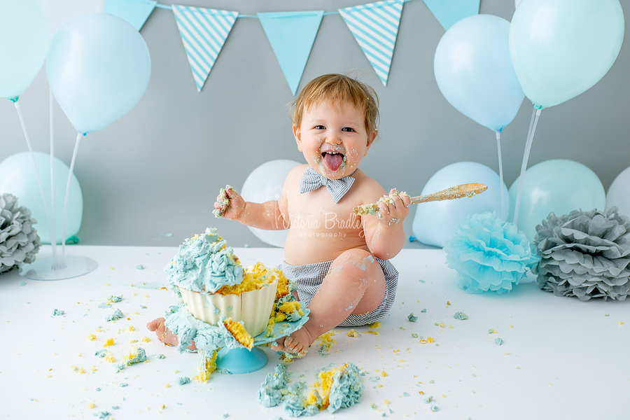 smiling baby boy cake smash with spoon