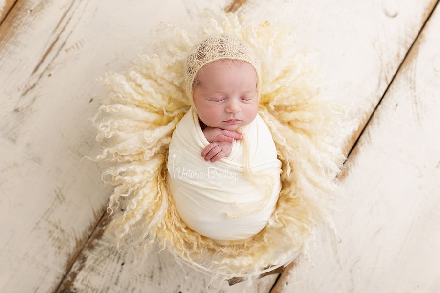 wrapped newborn on pale yellow