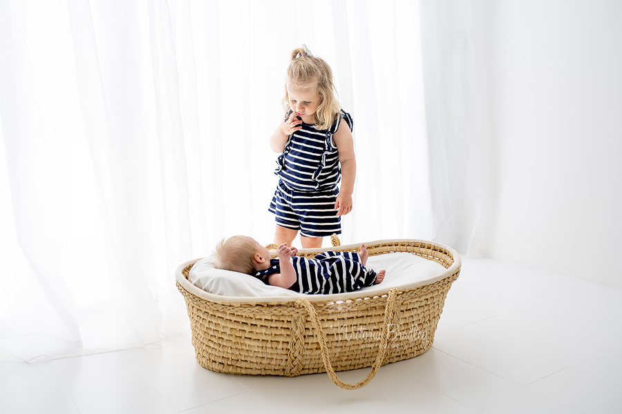 sibling and newborn Moses basket