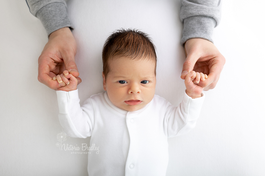 newborn boy holding hands