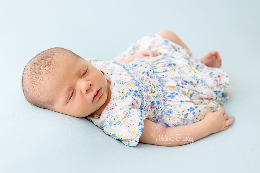 newborn girl in floral dress on blue