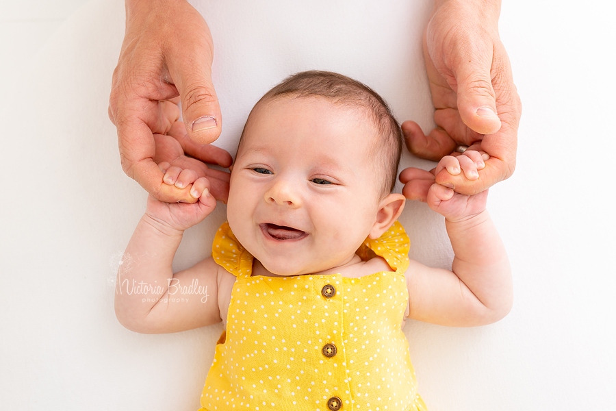 smiling newborn holding Daddy's hands
