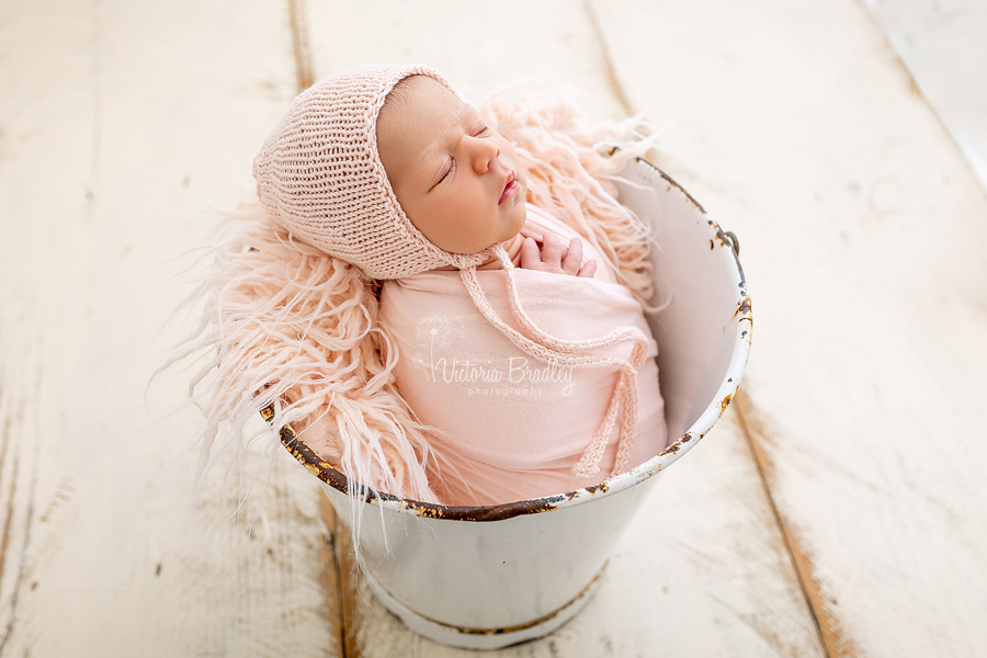 wrapped newborn in peach in white bucket