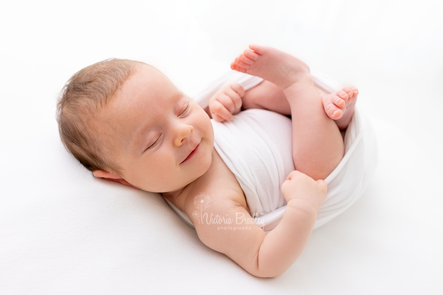 smiling newborn asleep on white