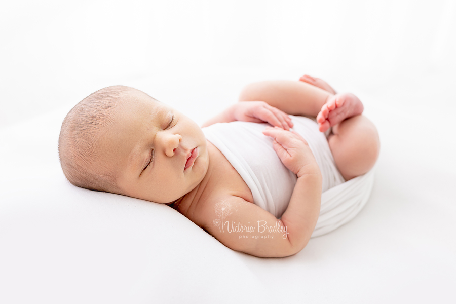 wrapped newborn on white backdrop