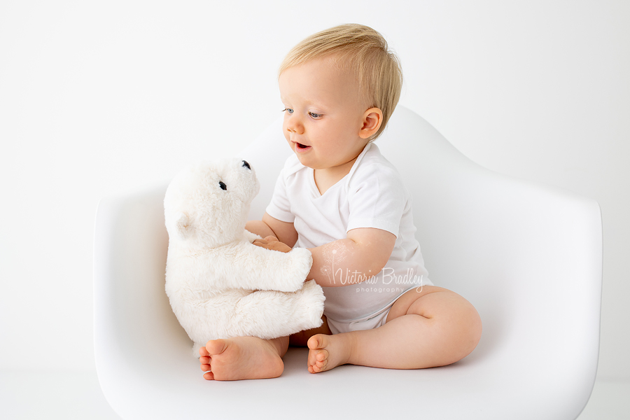 baby boy in white with white polar bear toy