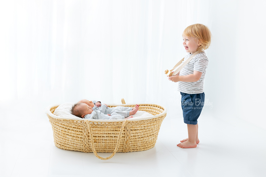 toddler taking photograph of twin newborns