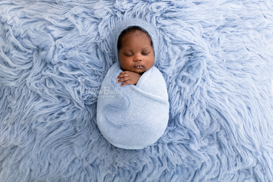 wrapped baby on blue flokati