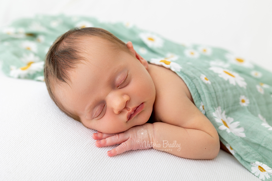 newborn girl on white with Daisey blanket