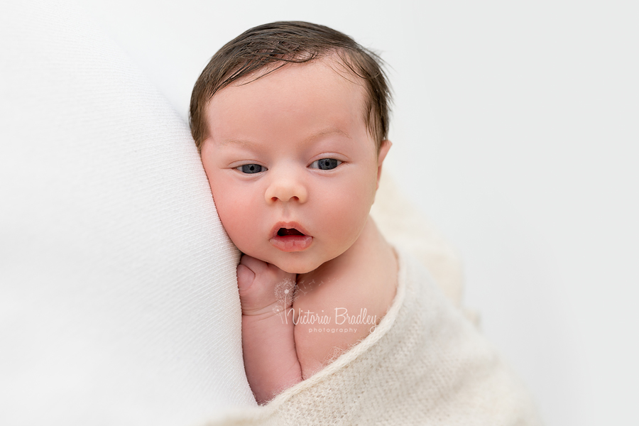 awake newborn boy on tummy