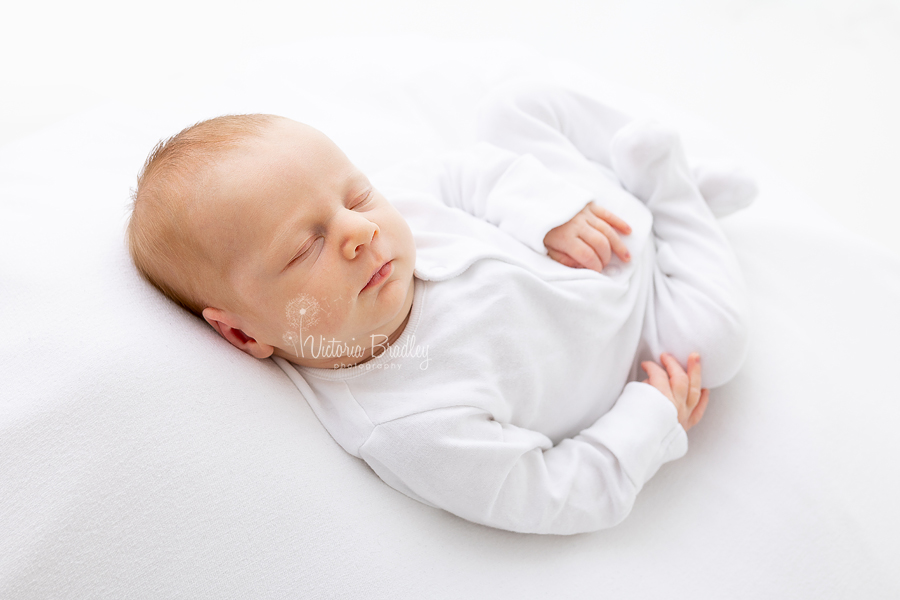 newborn in white sleepsuit