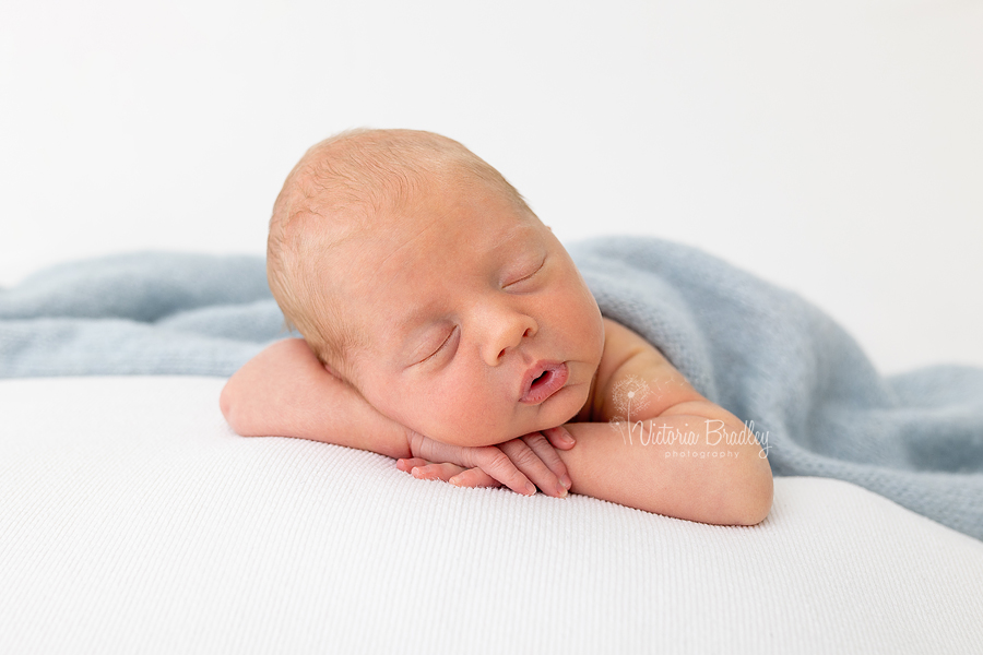 chin on hands pose newborn boy