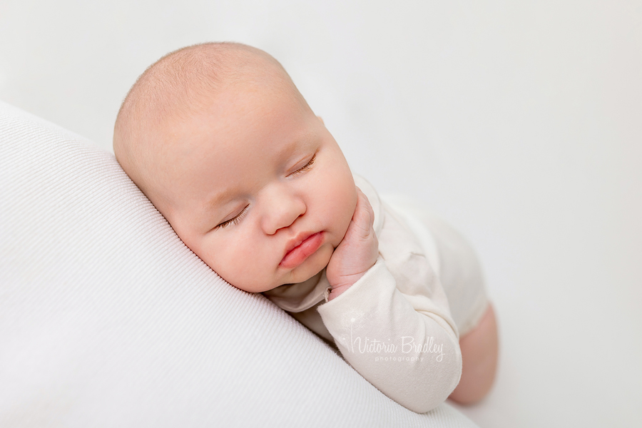 newborn baby asleep with hand on face