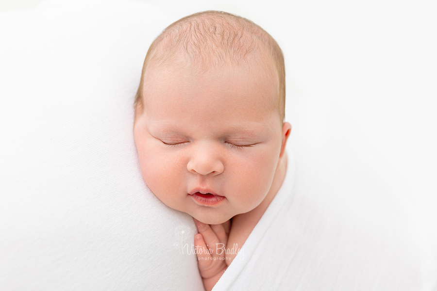 sleepy newborn on white backdrop