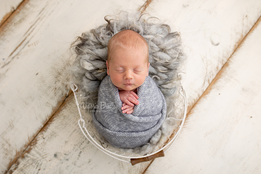 wrapped newborn boy in grey in basket