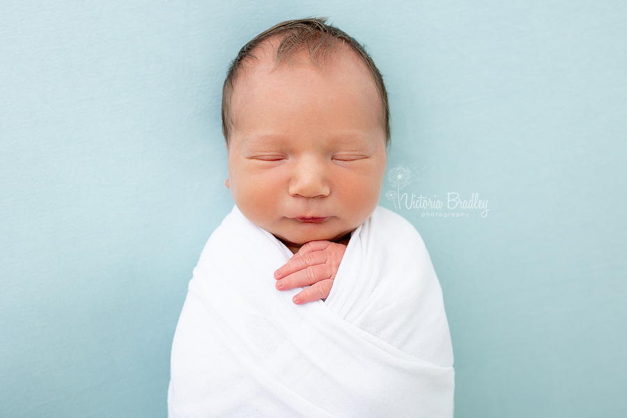 wrapped newborn on duck egg blue