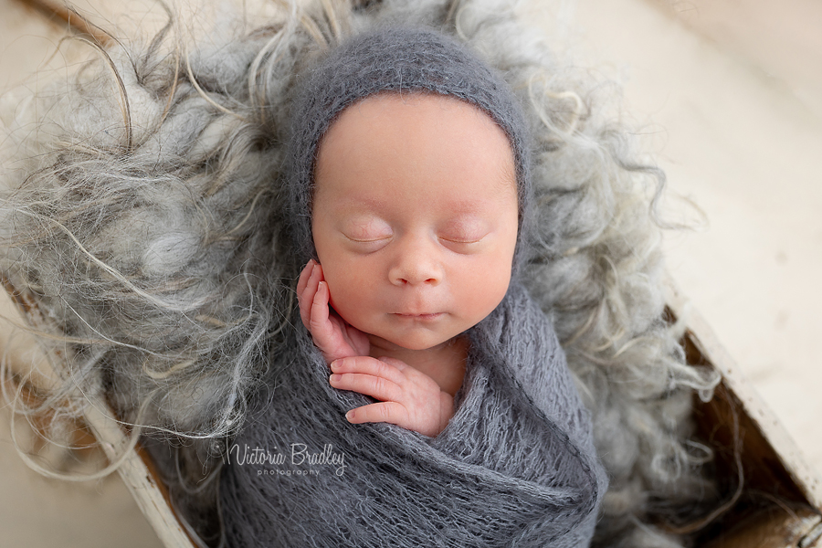 wrapped newborn girl in grey 