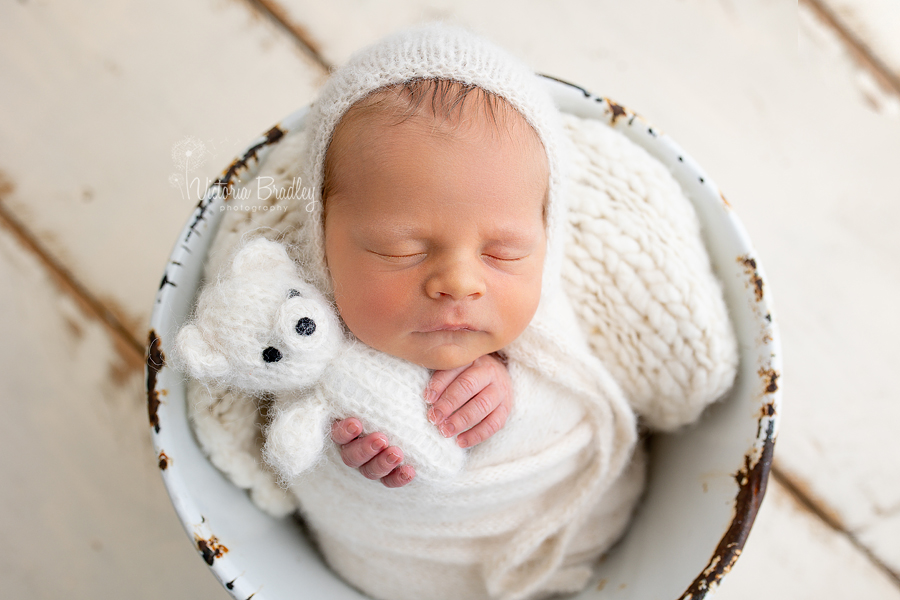 wrapped newborn baby holding little white teddy