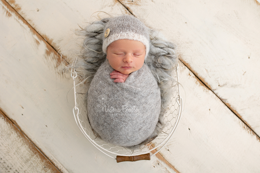wrapped newborn in grey, in basket