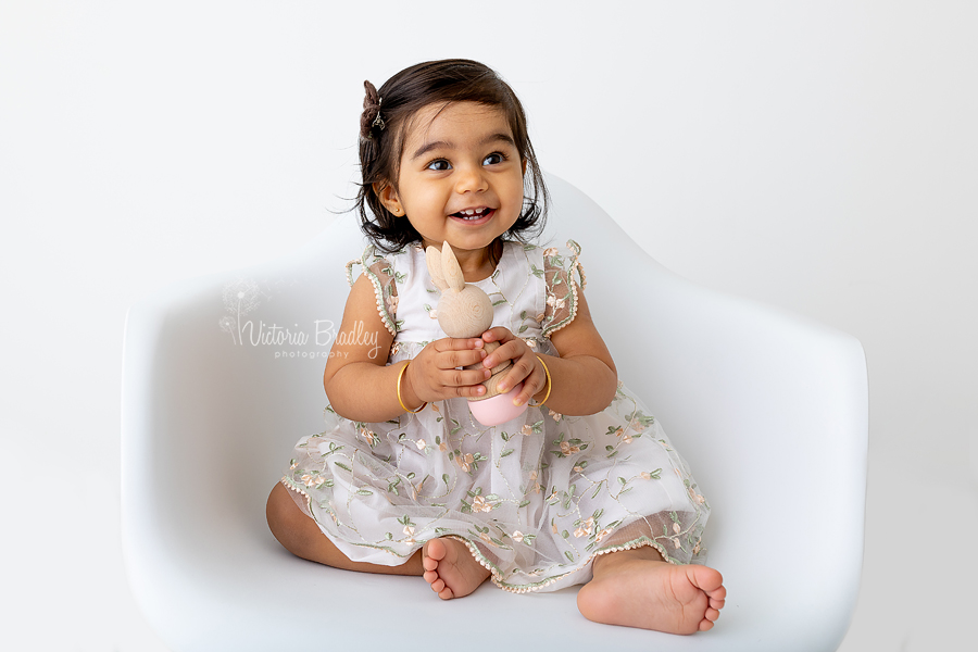 baby on white chair in floral dress