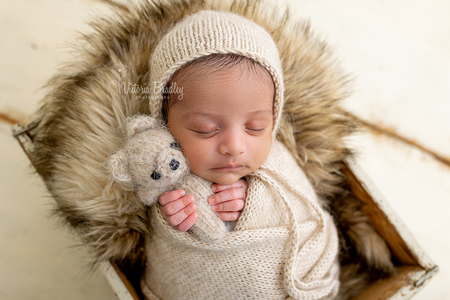 wrapped newborn baby with small knitted teddy